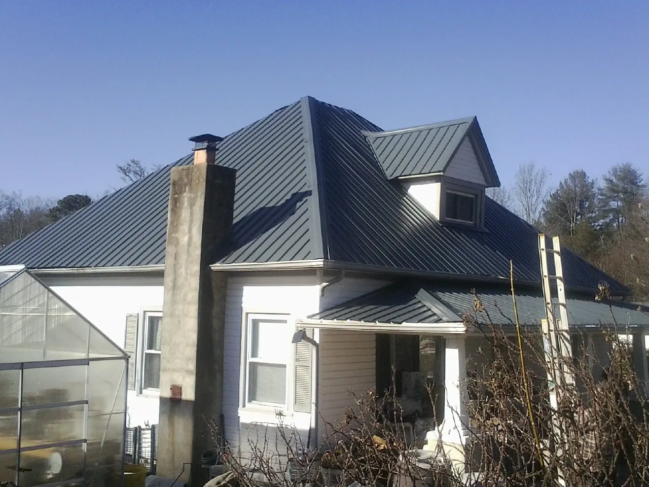 Dark blue standing seam metal roof on a white farmhouse with dormer — Slate & Tile Roof Repair by Roofing Brothers in Forked River