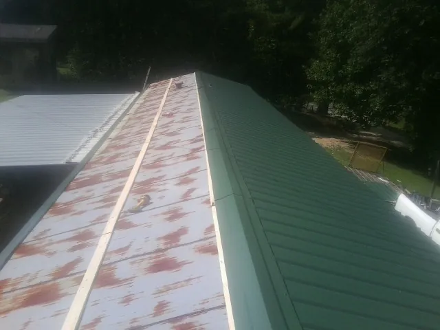 Old rusted panels beside newly installed green metal roofing — Wind Damage Roof Repair by Roofing Brothers in Forked River
