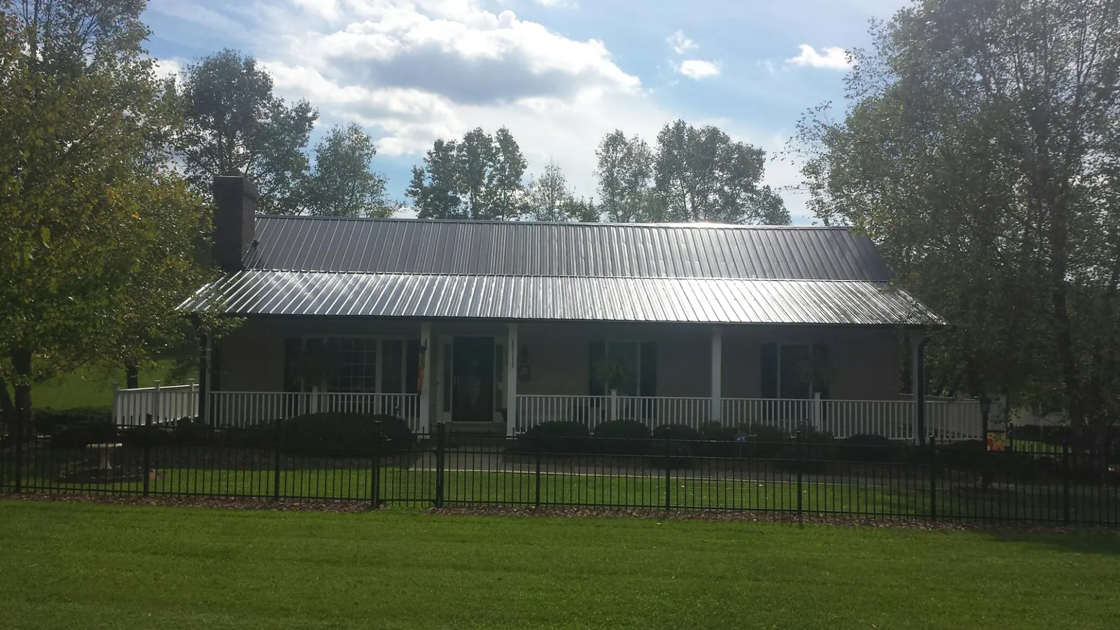 Gray metal roof on a brick ranch with a full width front porch — Gutter Guard Installation work by our crew in Forked River