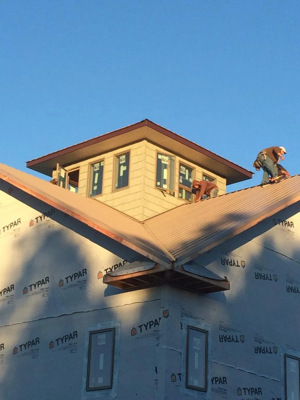 Roofers working around a rooftop cupola on a new metal roof at sunset — Roof Waterproofing in Forked River by Roofing Brothers